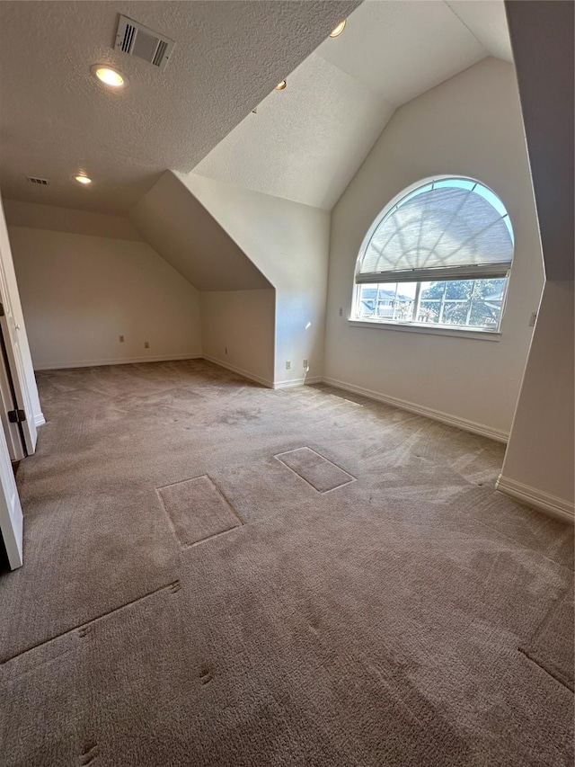 bonus room with visible vents, vaulted ceiling, and a textured ceiling