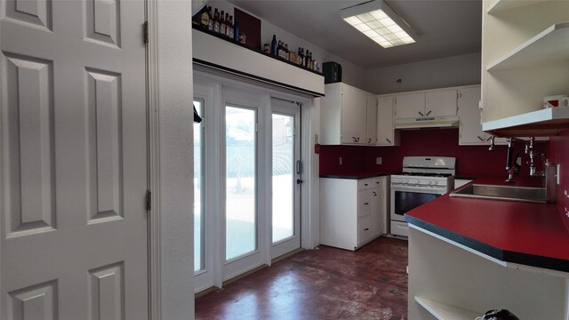 kitchen featuring under cabinet range hood, white range with gas stovetop, a sink, open shelves, and finished concrete floors