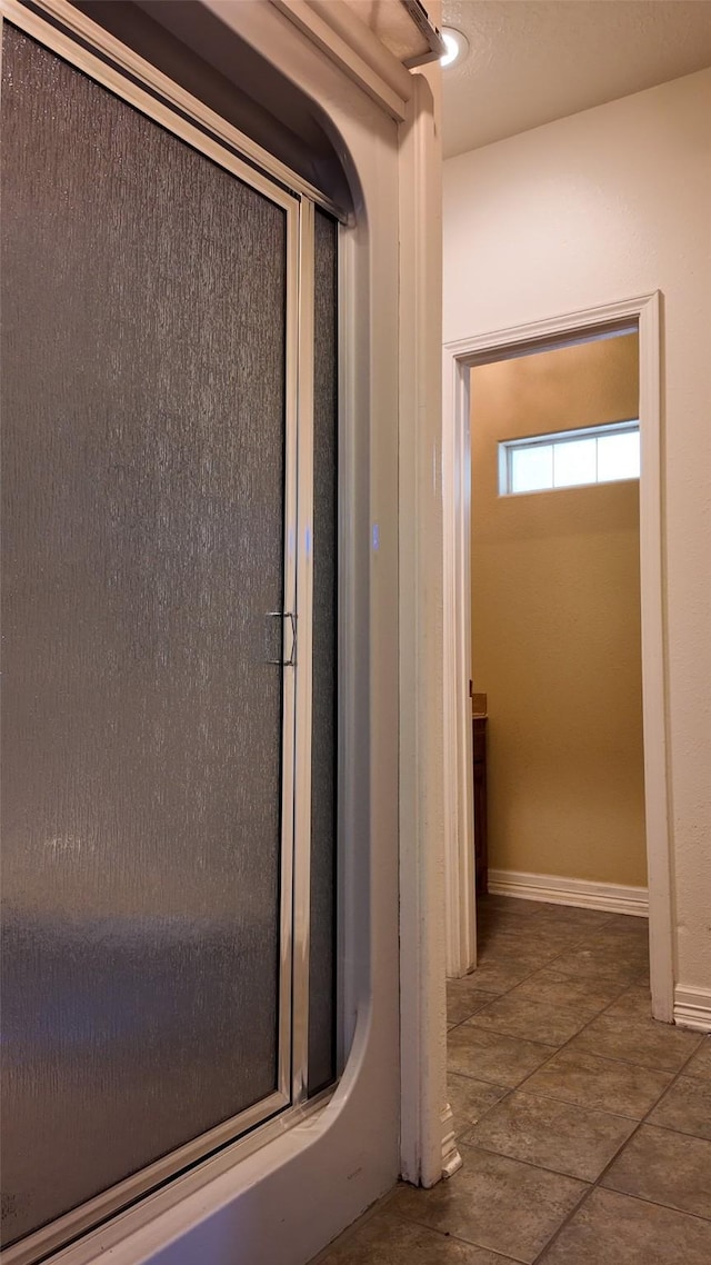 bathroom featuring tile patterned flooring, an enclosed shower, and baseboards