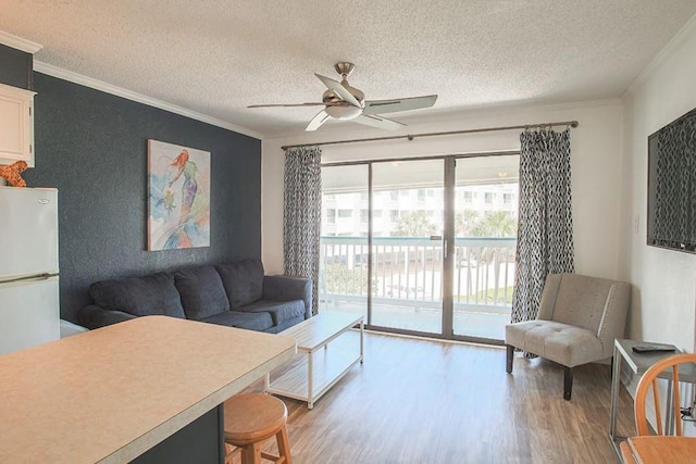 living area with light wood-style flooring, a ceiling fan, and ornamental molding