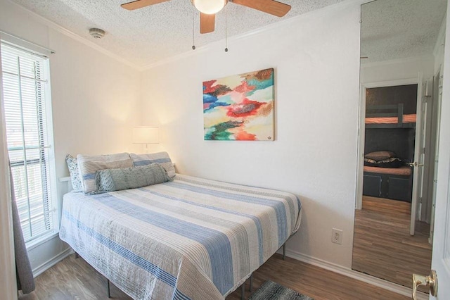 bedroom with a textured ceiling, crown molding, multiple windows, and wood finished floors