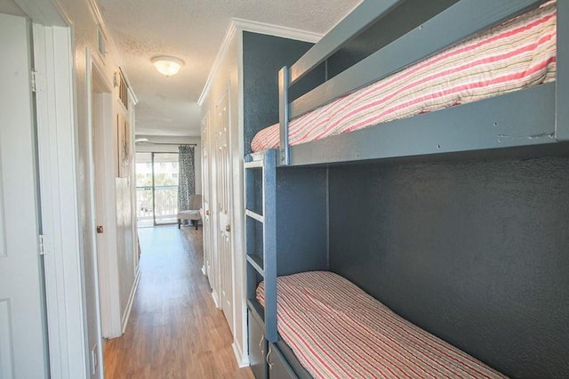 bedroom featuring a textured ceiling, wood finished floors, and crown molding