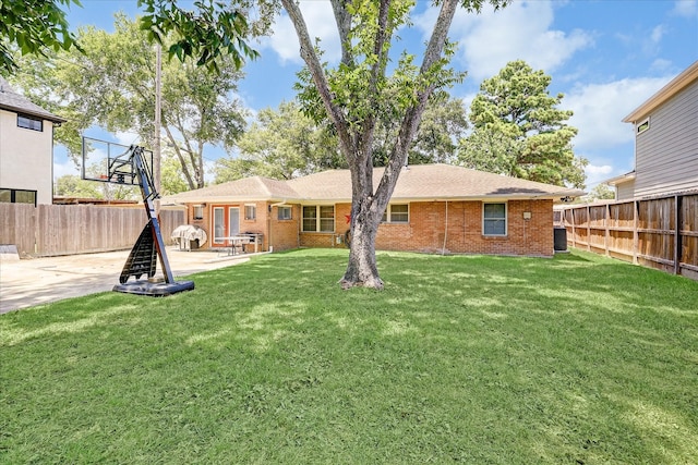 rear view of property with a fenced backyard, central AC unit, and brick siding