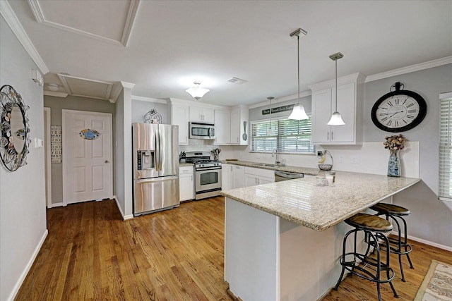 kitchen with a peninsula, appliances with stainless steel finishes, a sink, and white cabinetry