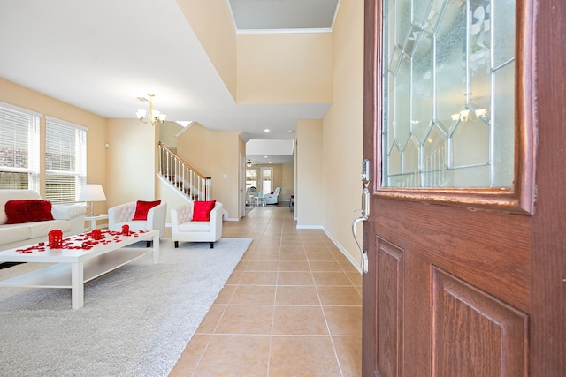 foyer entrance featuring crown molding, light tile patterned floors, stairway, a chandelier, and baseboards