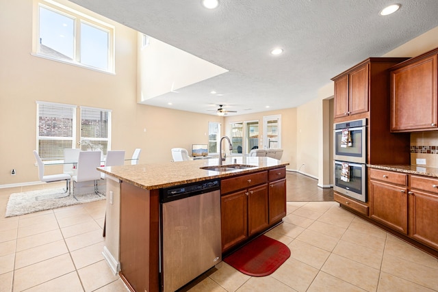 kitchen featuring light tile patterned floors, stainless steel appliances, an island with sink, and a sink