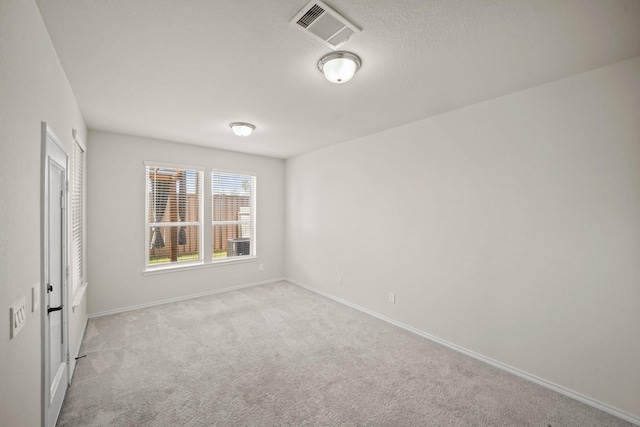 unfurnished room with baseboards, visible vents, a textured ceiling, and light colored carpet