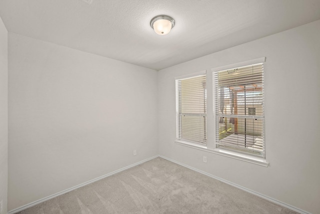 carpeted empty room featuring baseboards and a textured ceiling