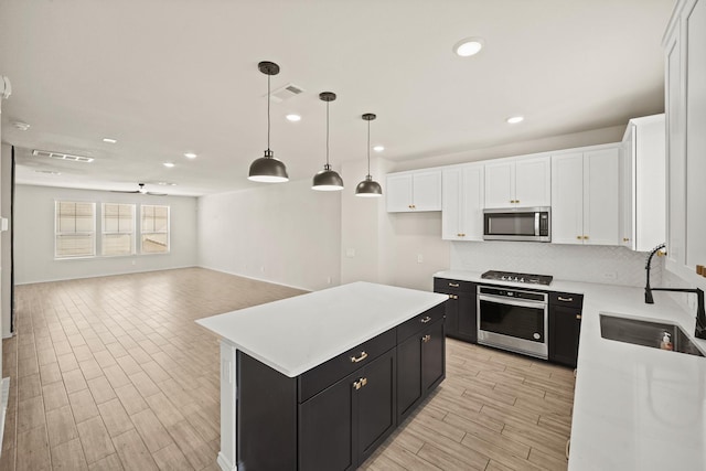 kitchen with visible vents, white cabinets, appliances with stainless steel finishes, dark cabinets, and a sink