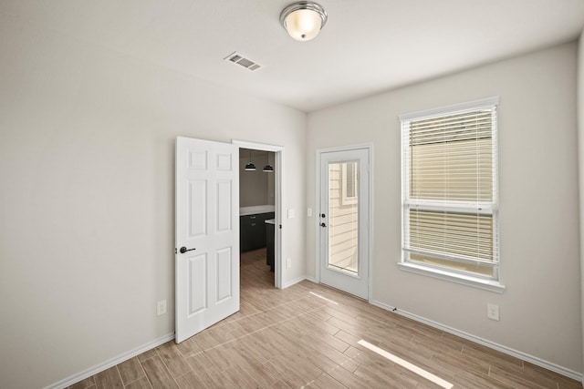 unfurnished room with light wood-type flooring, visible vents, and baseboards