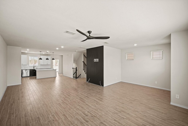 unfurnished living room featuring light wood finished floors, recessed lighting, visible vents, stairway, and ceiling fan