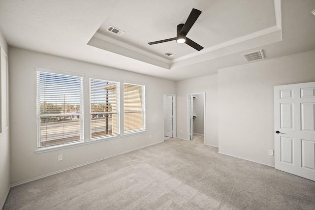 unfurnished bedroom with light colored carpet, a raised ceiling, and visible vents