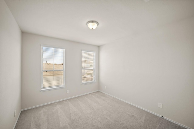 empty room featuring baseboards and light colored carpet