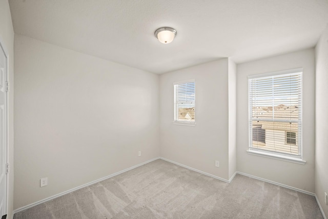 empty room featuring light colored carpet and baseboards