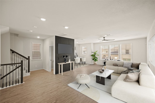 living room with light wood-type flooring, stairway, visible vents, and recessed lighting