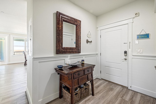 entryway featuring wainscoting, light wood-style flooring, and a decorative wall