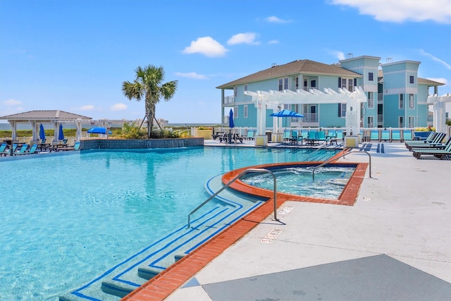 pool with a patio area and a hot tub