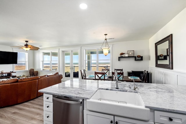 kitchen featuring a sink, light stone countertops, open floor plan, and stainless steel dishwasher