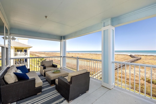 balcony with a water view, a beach view, and an outdoor living space