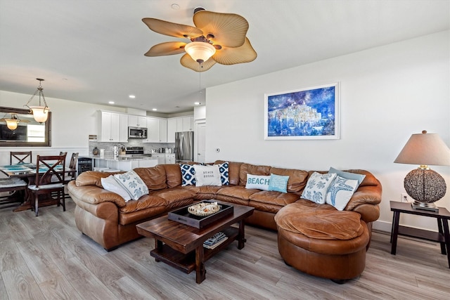 living area with light wood-style flooring, baseboards, a ceiling fan, and recessed lighting