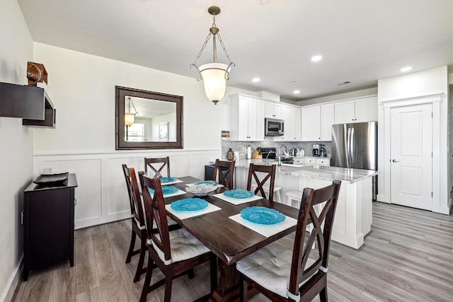 dining area featuring a decorative wall, recessed lighting, visible vents, light wood-style floors, and wainscoting