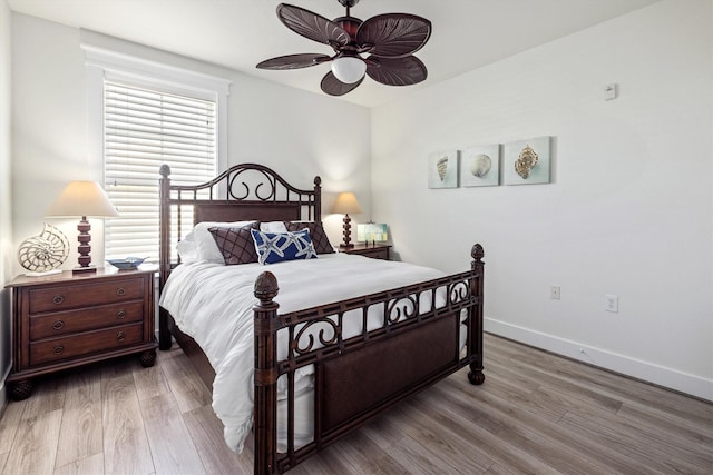 bedroom featuring a ceiling fan, baseboards, and wood finished floors