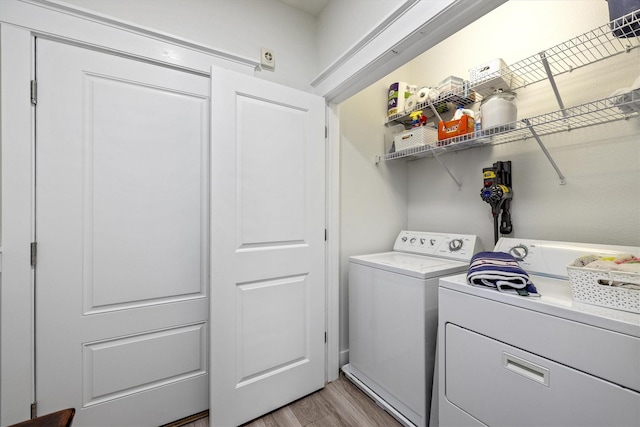 clothes washing area with light wood finished floors, laundry area, and separate washer and dryer