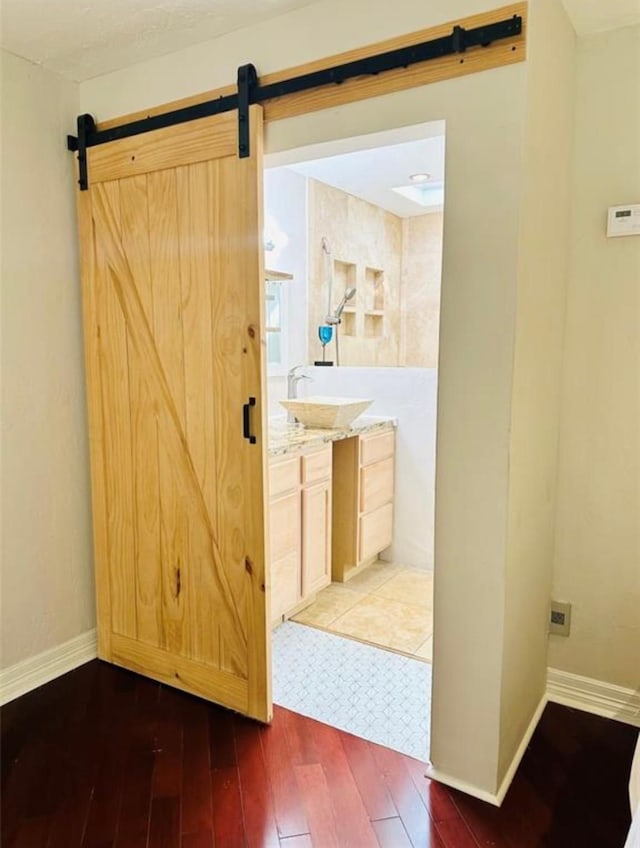 interior space with hardwood / wood-style flooring, a barn door, baseboards, and a sink