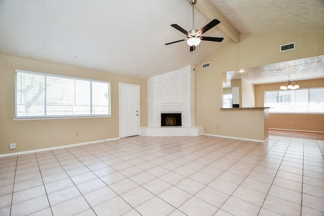 unfurnished living room featuring a textured ceiling, beamed ceiling, a fireplace, and visible vents