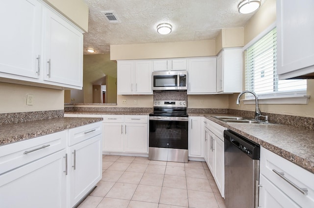 kitchen featuring stainless steel appliances, white cabinets, light tile patterned flooring, and a sink