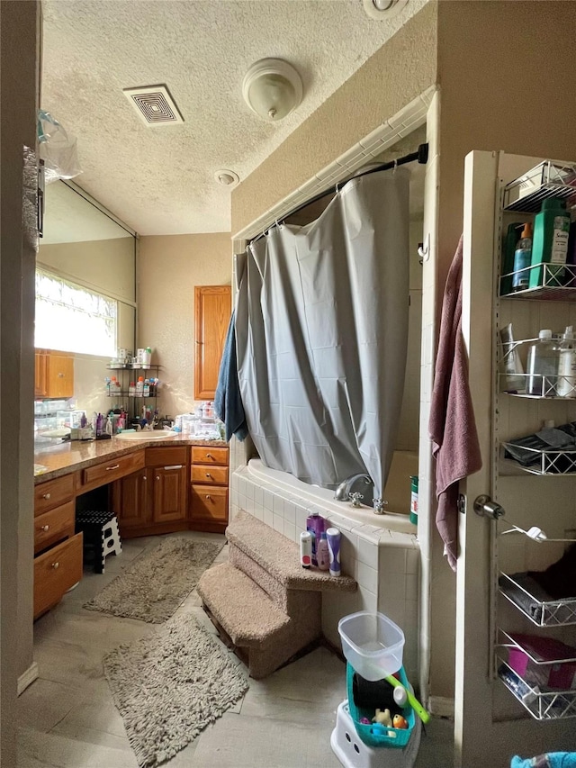 bathroom with a textured ceiling, vanity, and visible vents