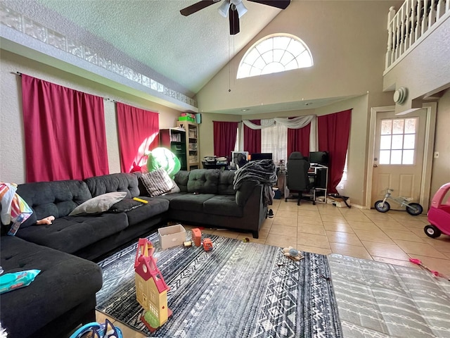 tiled living area with a textured ceiling, high vaulted ceiling, and a ceiling fan