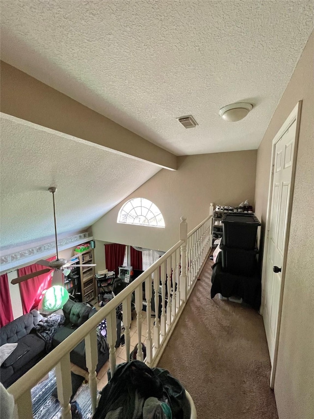 interior space with carpet flooring, vaulted ceiling with beams, visible vents, and a textured ceiling