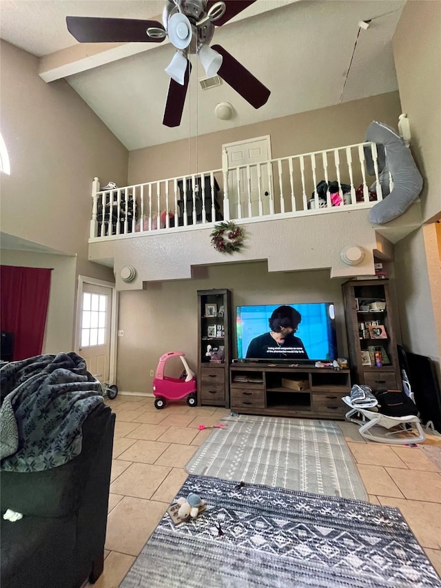 tiled living room featuring visible vents, baseboards, a ceiling fan, high vaulted ceiling, and beam ceiling