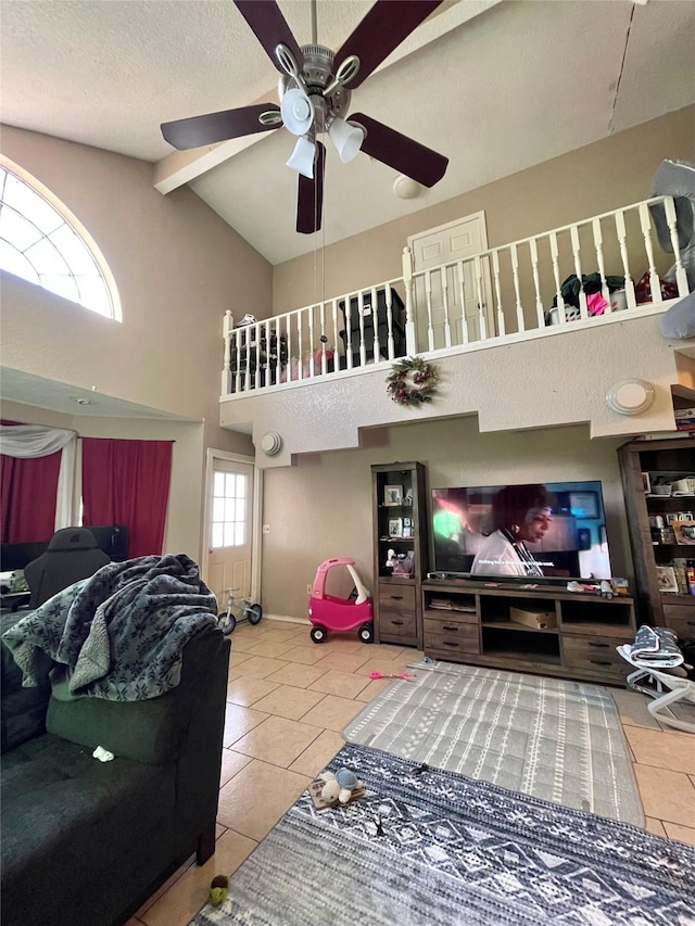 living area featuring ceiling fan, high vaulted ceiling, tile patterned flooring, baseboards, and beam ceiling