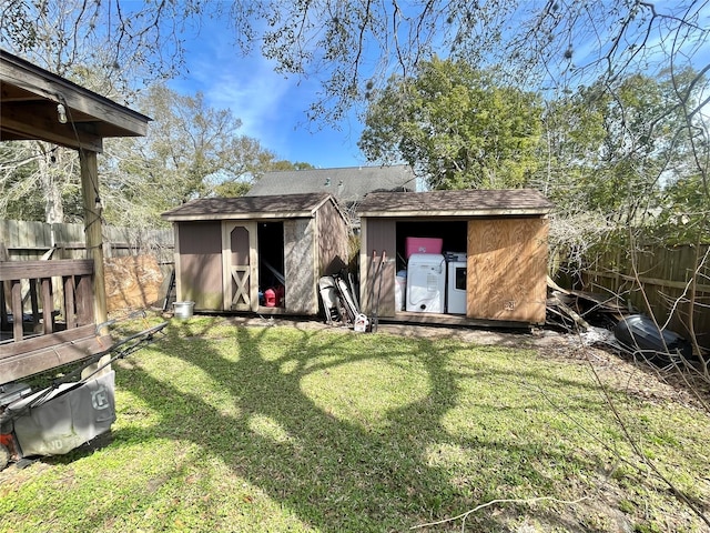 back of house featuring a fenced backyard, a lawn, an outdoor structure, and a shed