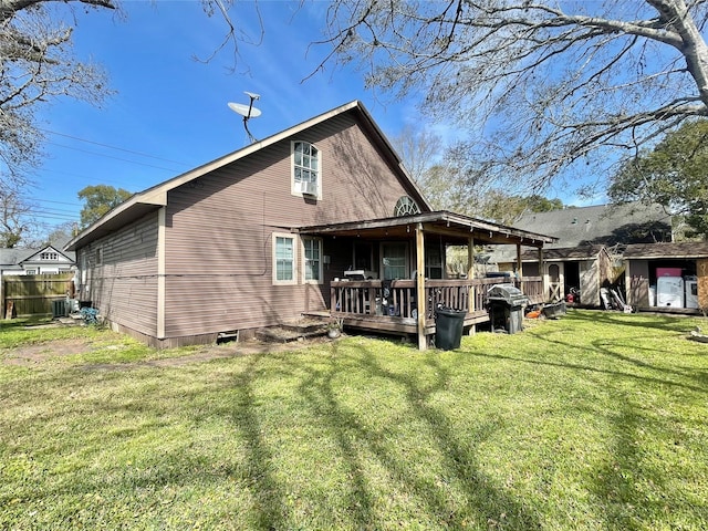 rear view of house with fence, a deck, a lawn, and an outdoor structure