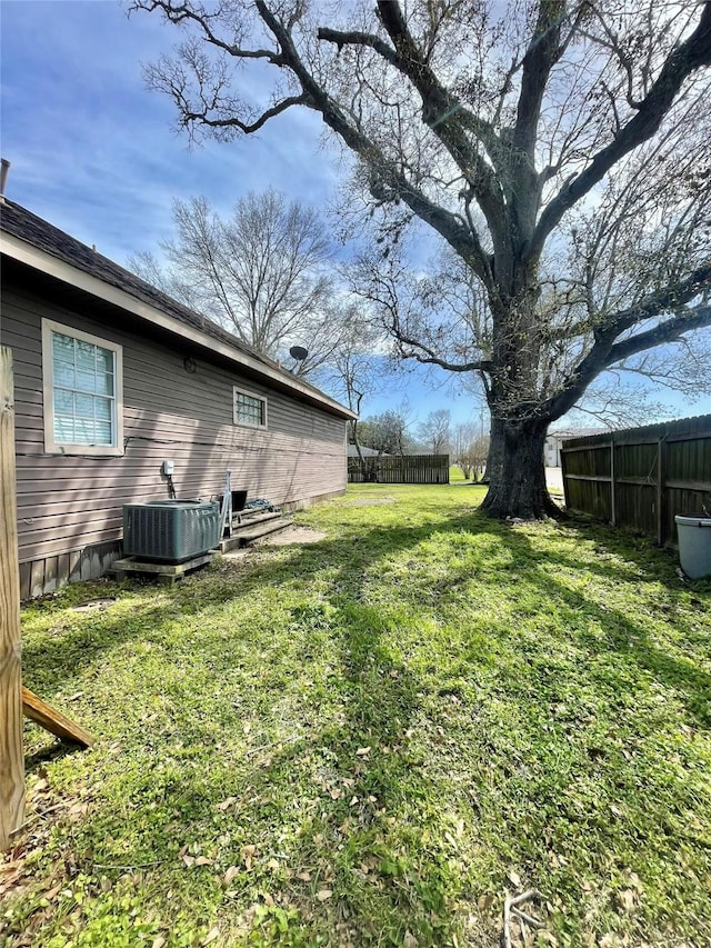 view of yard with central AC and fence