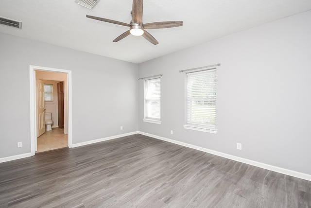 spare room with ceiling fan, wood finished floors, visible vents, and baseboards