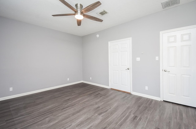 empty room featuring dark wood-style floors, visible vents, ceiling fan, and baseboards