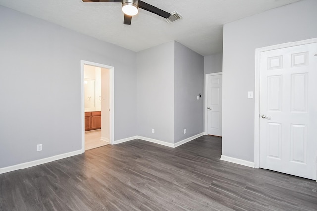 unfurnished bedroom featuring baseboards, visible vents, a ceiling fan, ensuite bath, and dark wood-type flooring