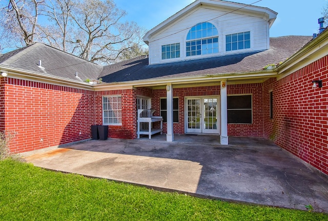 back of house with brick siding, a shingled roof, a patio area, and french doors