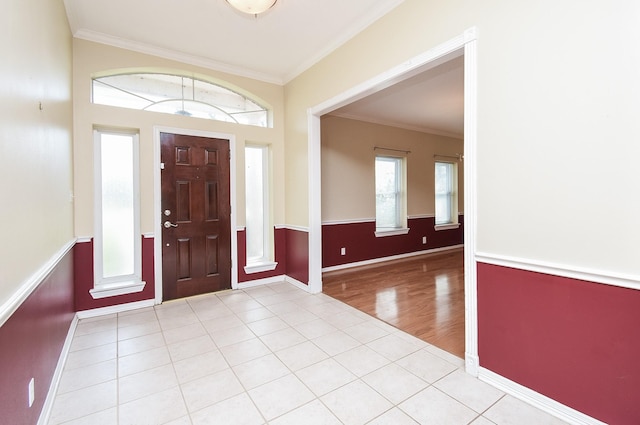 entryway featuring light tile patterned floors, baseboards, and crown molding