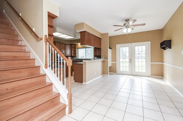 kitchen with brown cabinetry, ceiling fan, open floor plan, a peninsula, and french doors