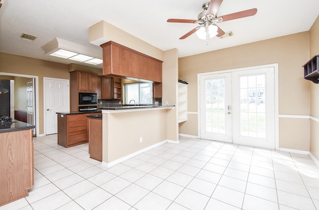 kitchen with tasteful backsplash, visible vents, brown cabinetry, a peninsula, and black appliances