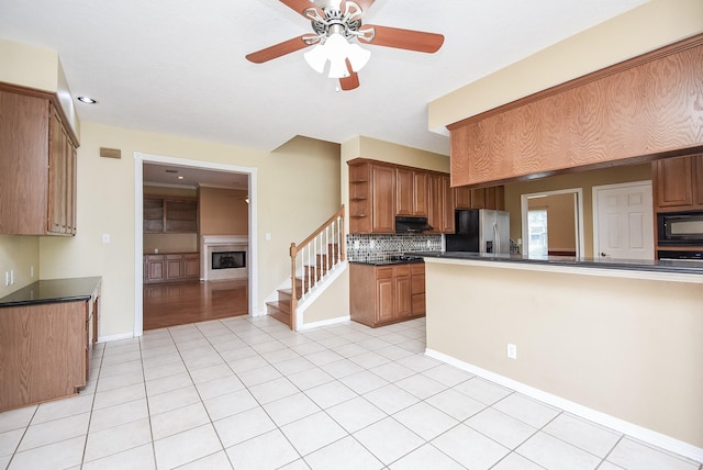 kitchen with black microwave, backsplash, open shelves, dark countertops, and stainless steel fridge