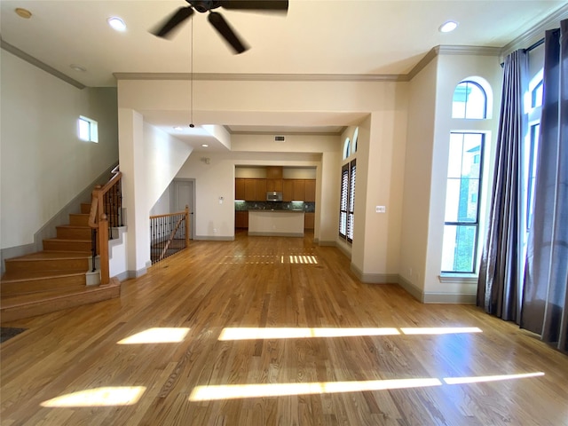 unfurnished living room featuring crown molding, recessed lighting, light wood-style floors, baseboards, and stairs