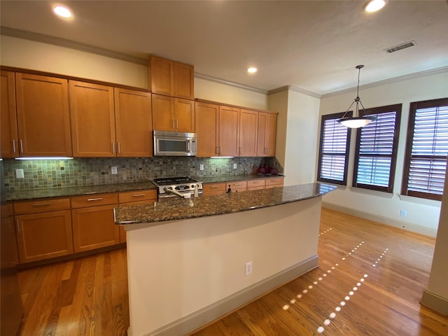 kitchen featuring brown cabinets, light wood-style floors, stainless steel appliances, and crown molding