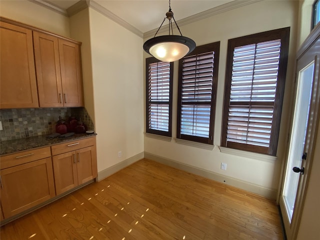 unfurnished dining area with ornamental molding, baseboards, and light wood finished floors