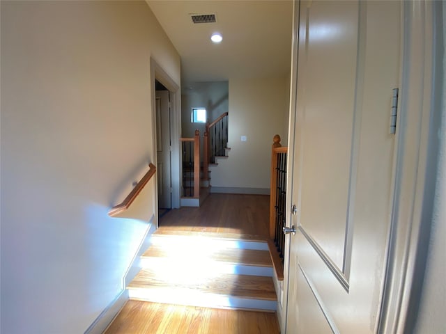 corridor with baseboards, visible vents, stairway, light wood-type flooring, and recessed lighting